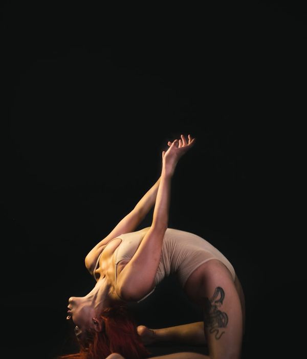 Graceful woman performing a yoga stretch in a dark room.